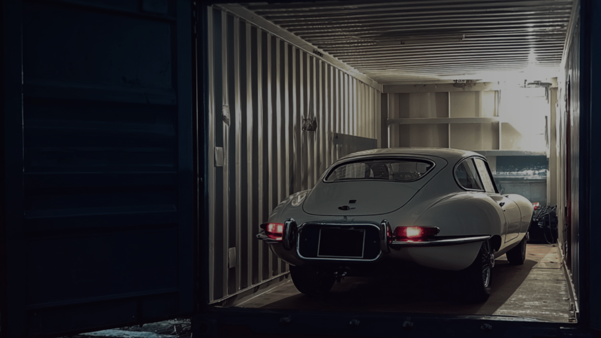 Classic white Jaguar E-Type inside a shipping container.